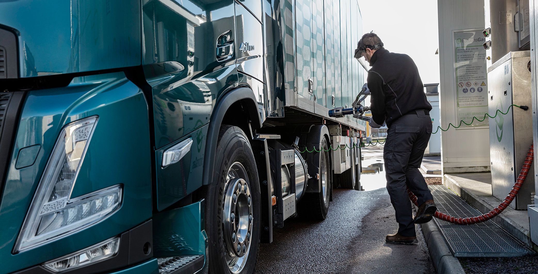 Man standing besides a truck by a gas station