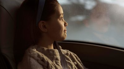 A little girl looks out the window of a coach