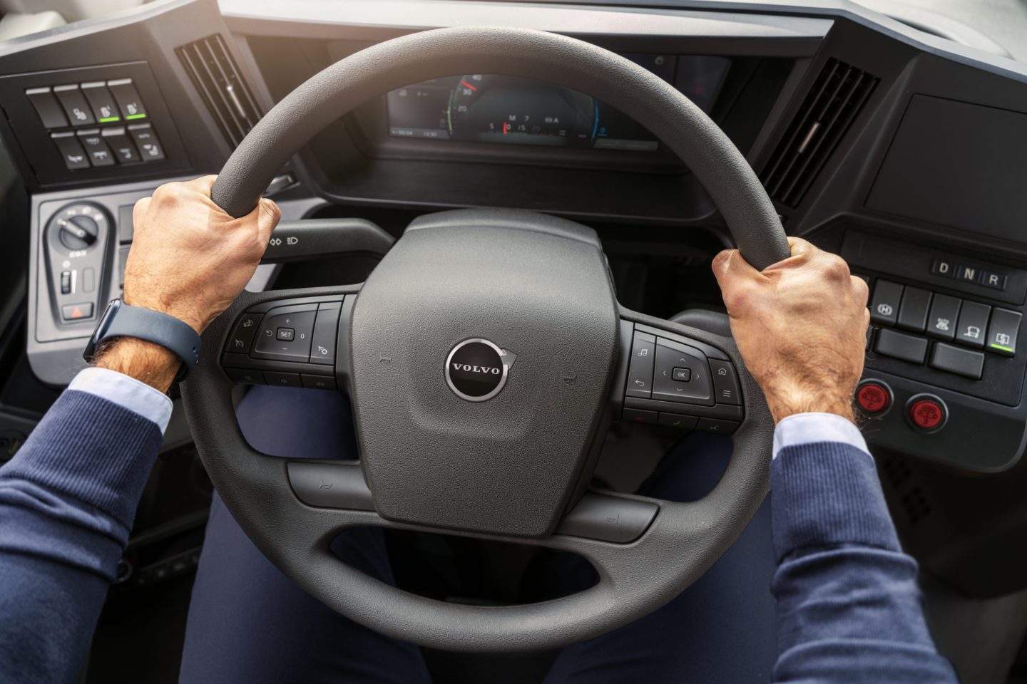 A bus driver’s hand with a firm grip of the steering wheel of a Volvo electric bus