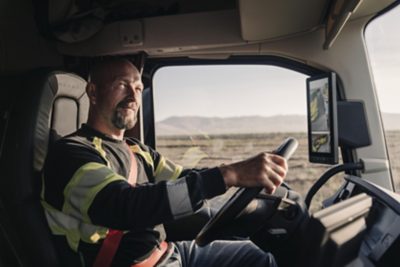 Um homem com um carrinho de mão passa por um camião dentro duma plataforma de carga