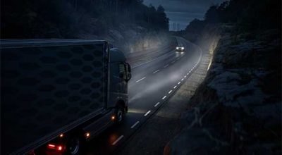  Self driving Volvo truck driving on a road at night, meeting a Volvo car in the opposite car lane.