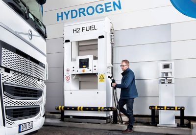 En man på en H2-bränslestation som tankar en Volvolastbil I Volvokoncernen