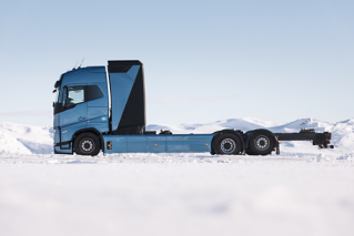מבט מהצד על משאית תא דלק חשמלית בנסיעת מבחן בשלג