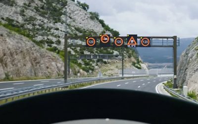 Camion roulant sur une route avec montagnes sur le côté et panneaux routiers 