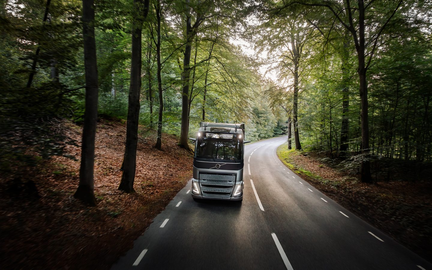 Volvo FH dikemudikan di jalan melalui hutan