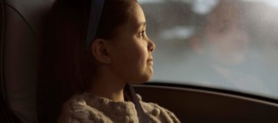 A young girl looking out a bus window