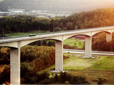 A Volvo bus on a high bridge over a motorway