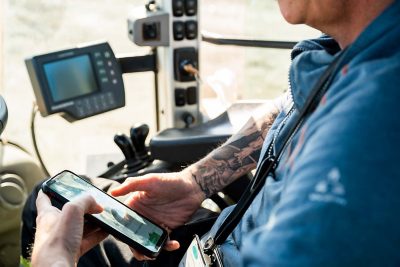 Mann i styrhus på lastebil holder en mobil med Linx på skjermen. 