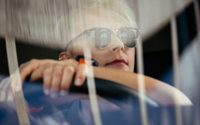 Fahrer im Fahrerhaus, mit Sonnenbrille und Händen am Lenkrad