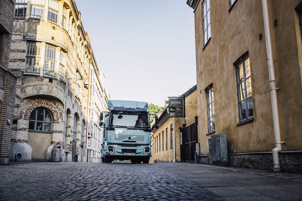 Blue FL electric truck driving on a cobbled street in the inner city