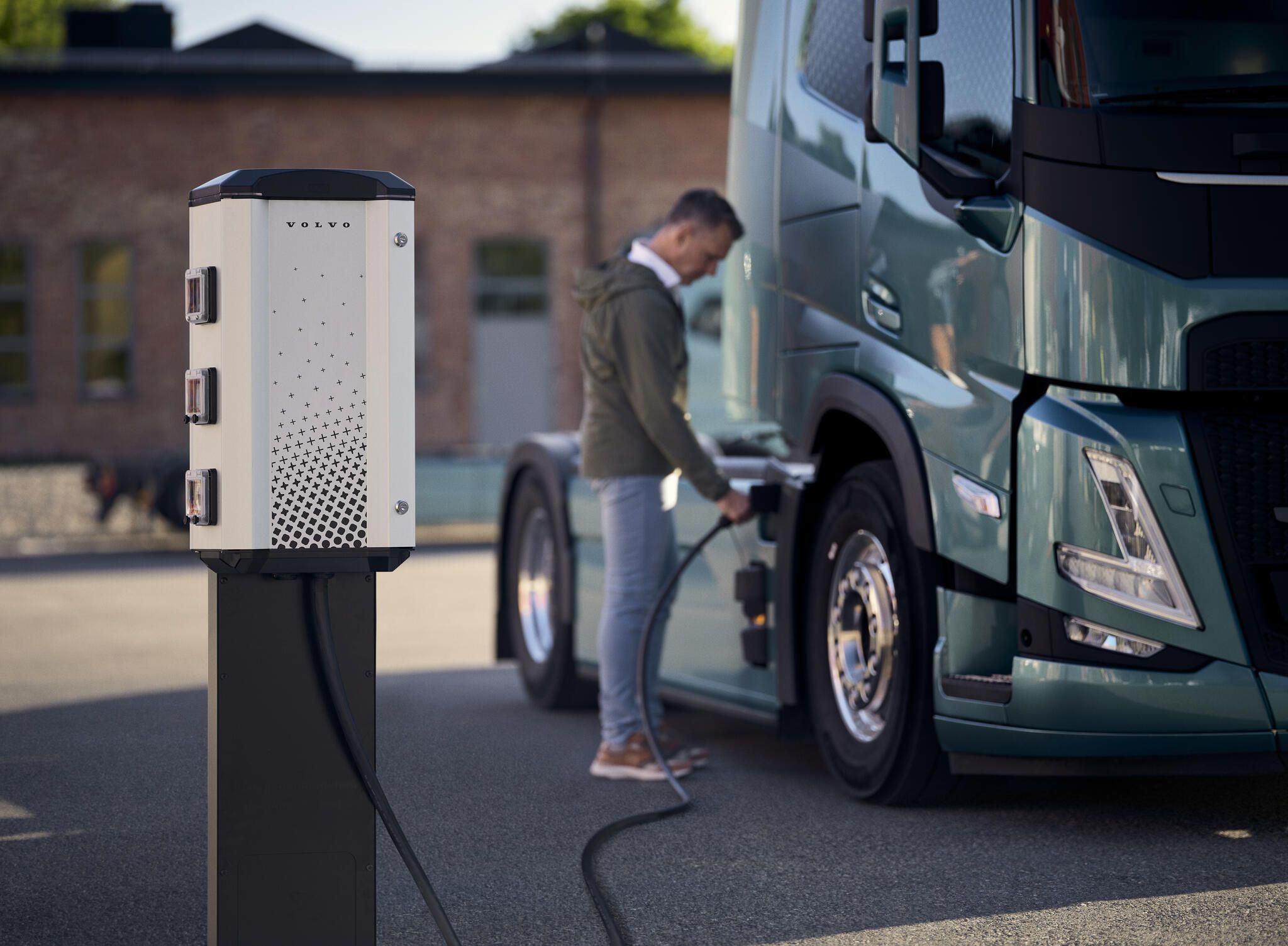 Image of a man charging his electric truck from a Volvo charging station