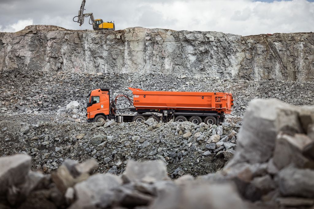 An orange Volvo Truck in a mining field.