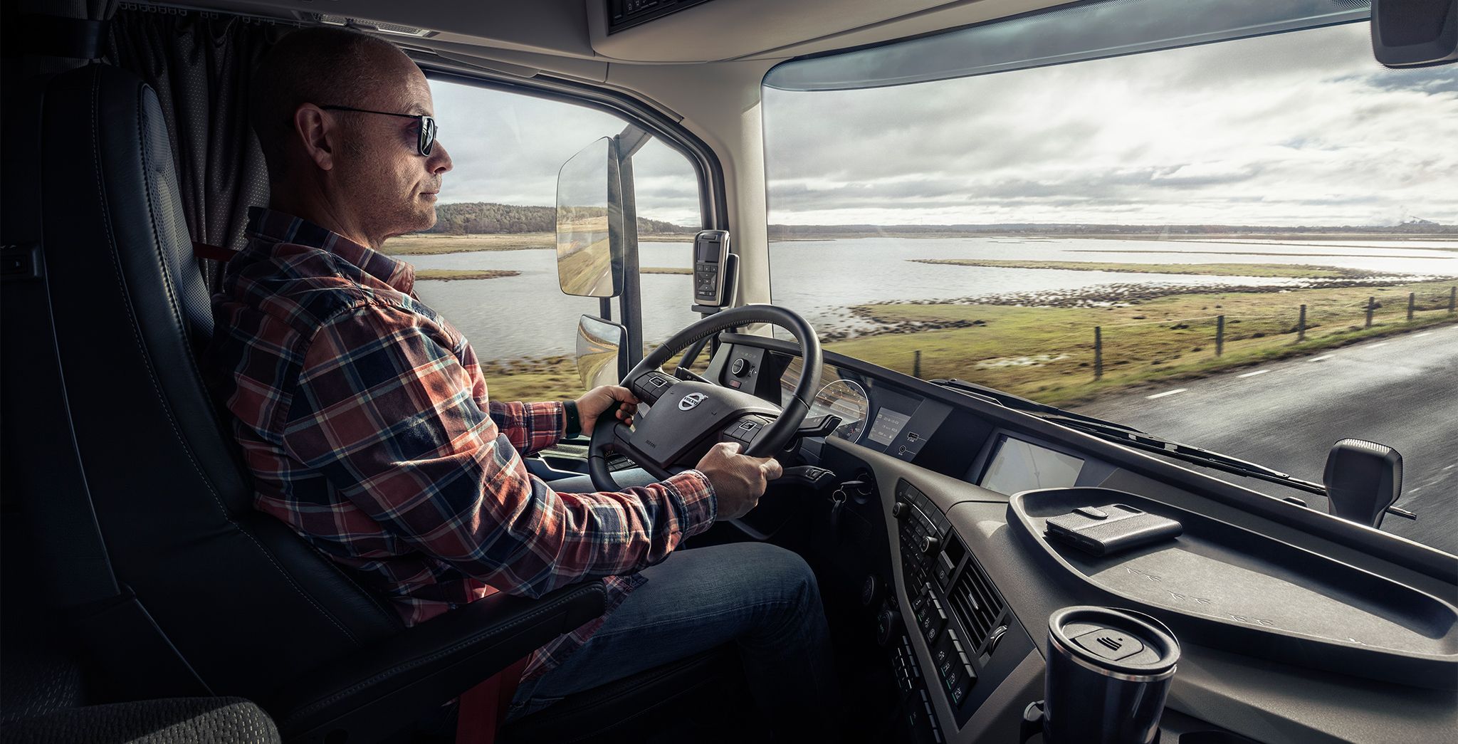 Male driver driving a truck on a road beside water