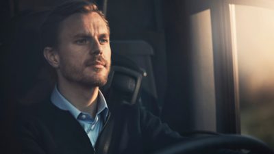 A confident male driver behind the steering wheel of a bus. 