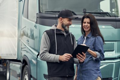 Mand og kvinde kigger på tablet foran Volvo FH Aero Electric