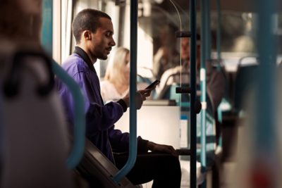 A passenger onboard a Volvo 7900 Electric bus, looking at his phone