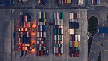  An image taken from above in a port, showing cargo stacked in rows.