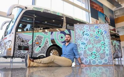 Goreng Goreng Artist Jacob Sarra with his untitled commissioned artwork for Volvo Group Australia in front of the wrapped Sunstate Charters Volvo B8R bus ahead of NAIDOC Week.