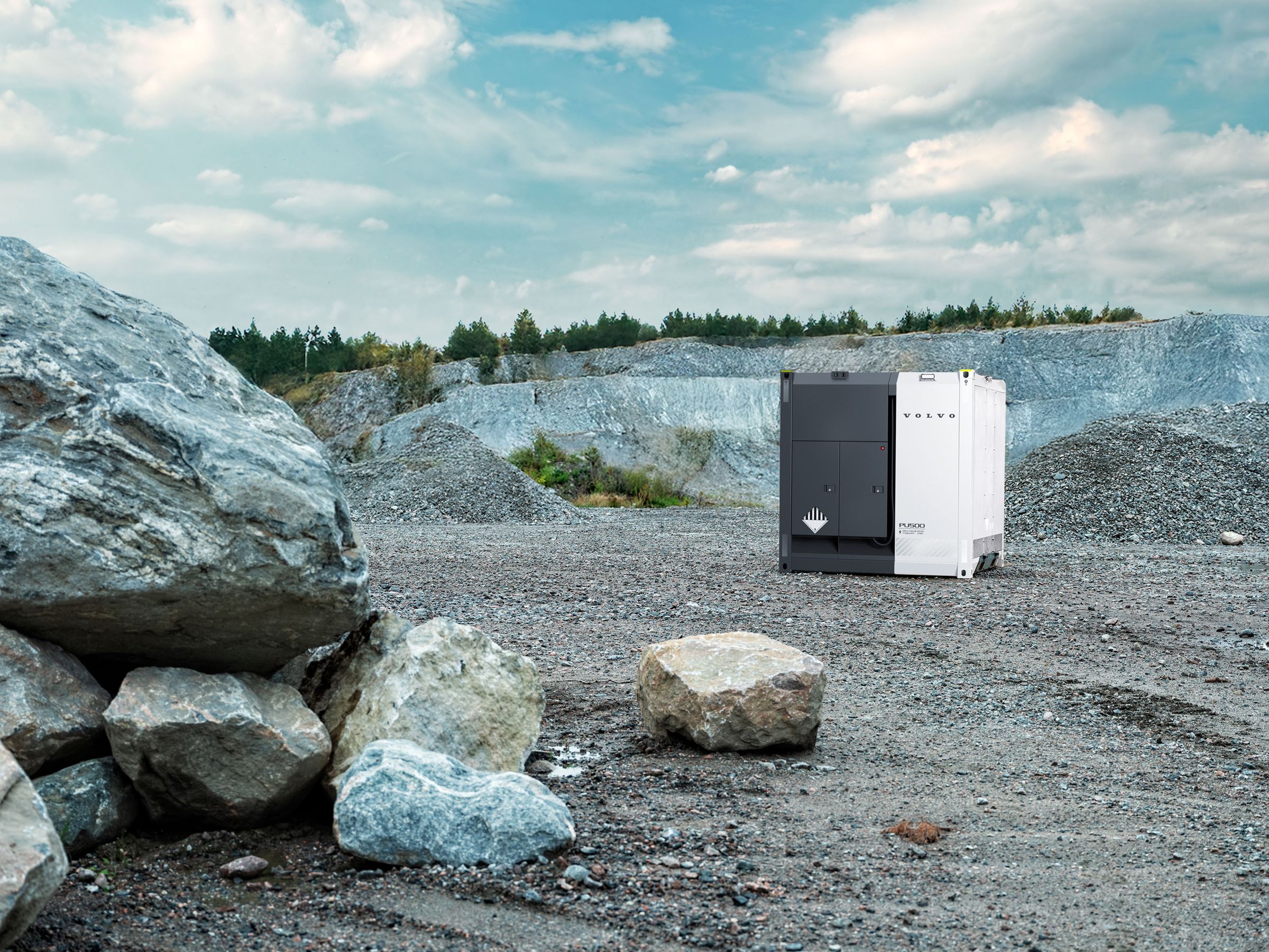 The image shows a PU500 in a quarry with a few boulders in the foreground
