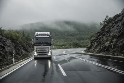 A truck drives around a bend through the rain