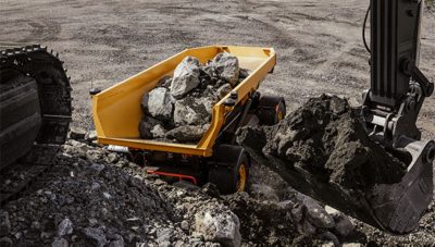 Volvo TA15 electric dumper is being filled with large stones from an excavator in a quarry.