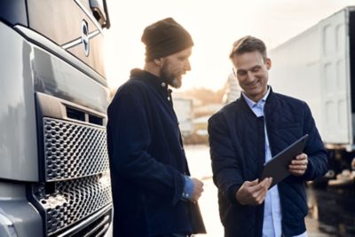 Sales rep/dealer and customer with tablet in front of truck (FH)                 