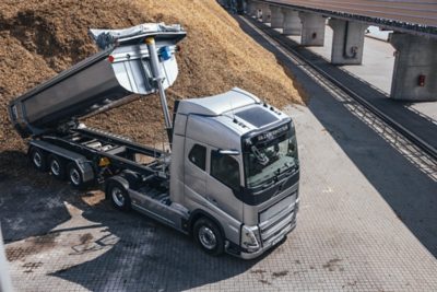 A man with a handtruck walks by a truck inside a loading dock