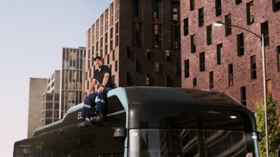 A Volvo service technician sitting on the roof of a Volvo 8900 Electric bus.