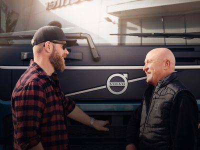 Two men speak in front of a Volvo truck