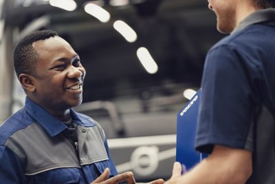 A smiling Volvo service technician speaks to a colleague