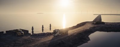 A truck drives over a bridge with mountains in the background