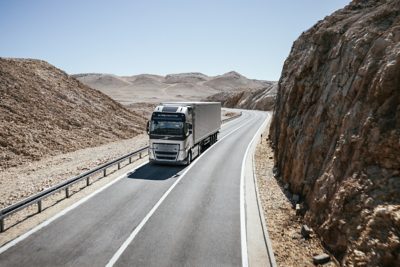 Een voertuig rijdt door een bergachtig woestijnlandschap