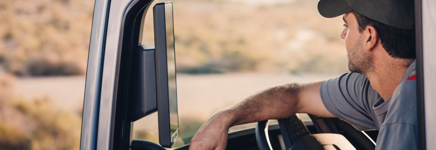 A Volvo service technician holding a computer looks at a truck