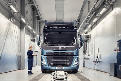 Технічна працівниця Volvo тримає комп’ютер, стоячи біля вантажівки