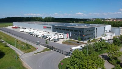 Luftaufnahme des Logistikzentrums von Pabst Transport in Gochsheim mit mehreren Volvo-Lkw und Photovoltaikanlage auf dem Hallendach.