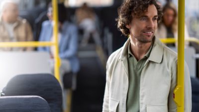 A smiling male passenger standing up in a bus