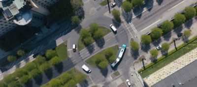 Aerial shot of a bus going around a roundabout with trees