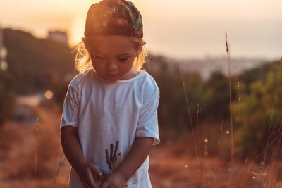 Cute little boy on the walk, sweet child with pleasure spending time outdoors, enjoying warm summer evening and beautiful sunset