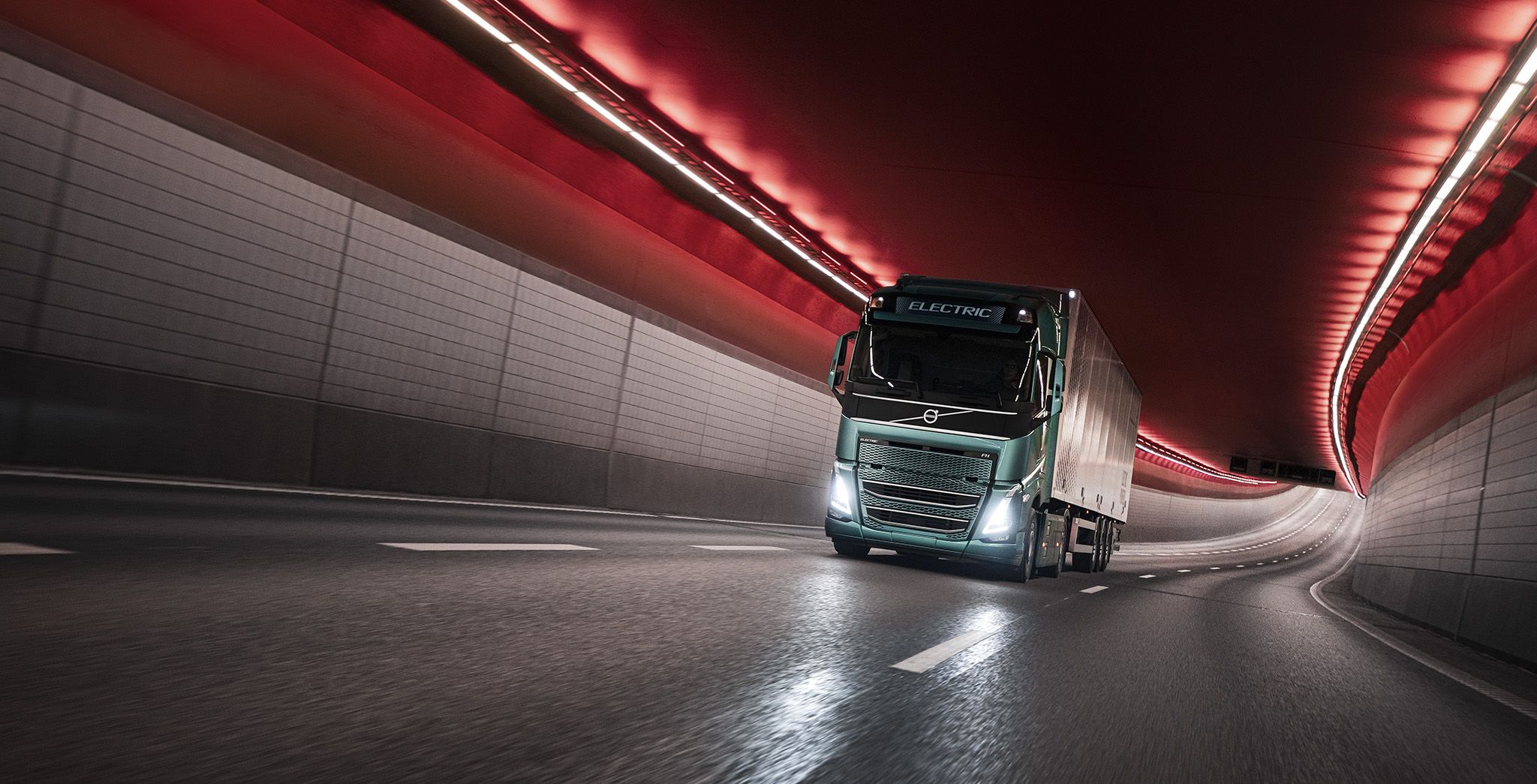 Electric truck driving through a red-lit tunnel.