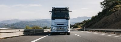 „Volvo“ sunkvežimis važiuoja tiesiai keliu, kurio fone matyti kalnai