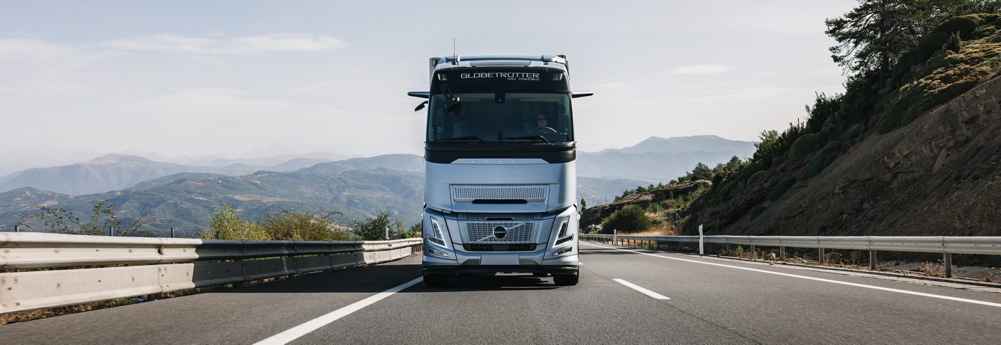 Volvo kamion pravo napred na putu sa planinama u pozadini