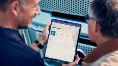 Mechanic and truck driver talking in warehouse in front of Volvo FH Electric