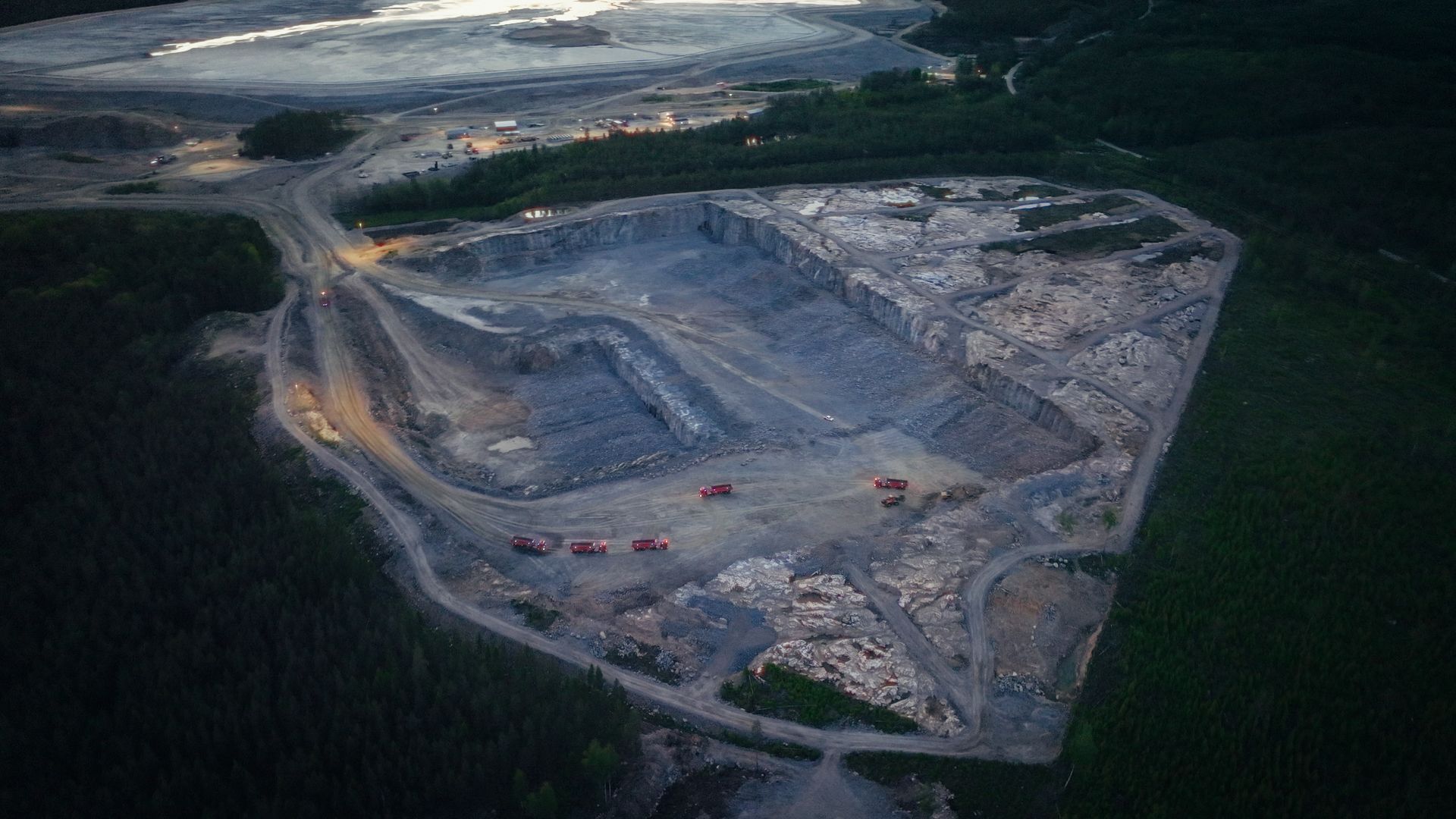 Aerial view of a quarry with 5 volvo autonomous trucks running inside them.