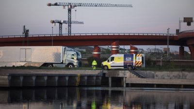 Un véhicule Volvo Action Service garé à côté d'un camion sous une passerelle