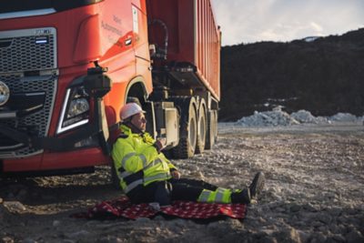 Man sitting on the ground in front of a truck