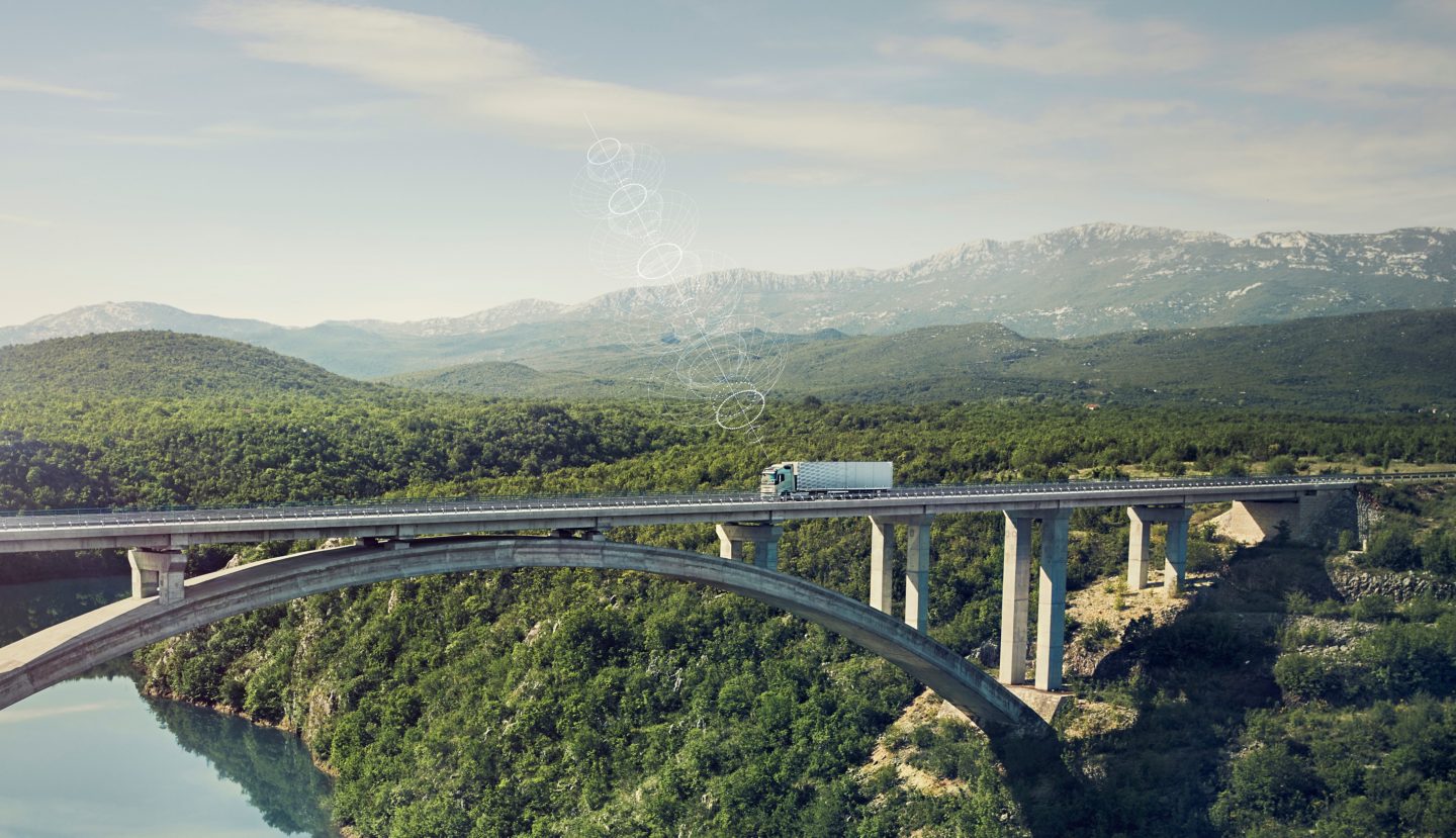 A connected Volvo Truck drives over a bridge in a remote location
