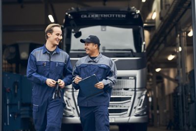 Two Volvo service technicians look at a laptop while standing next to a truck 