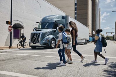 Volvo truck on city street with pedestrians crossing