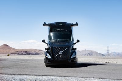 Volvo truck driving on a highway with  a city skyline in the background