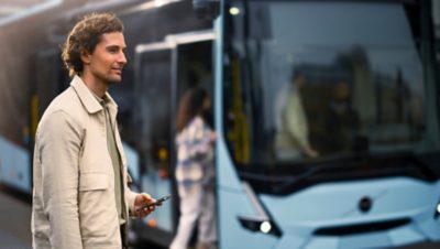 Man with mobile phone in front of a Volvo electric bus